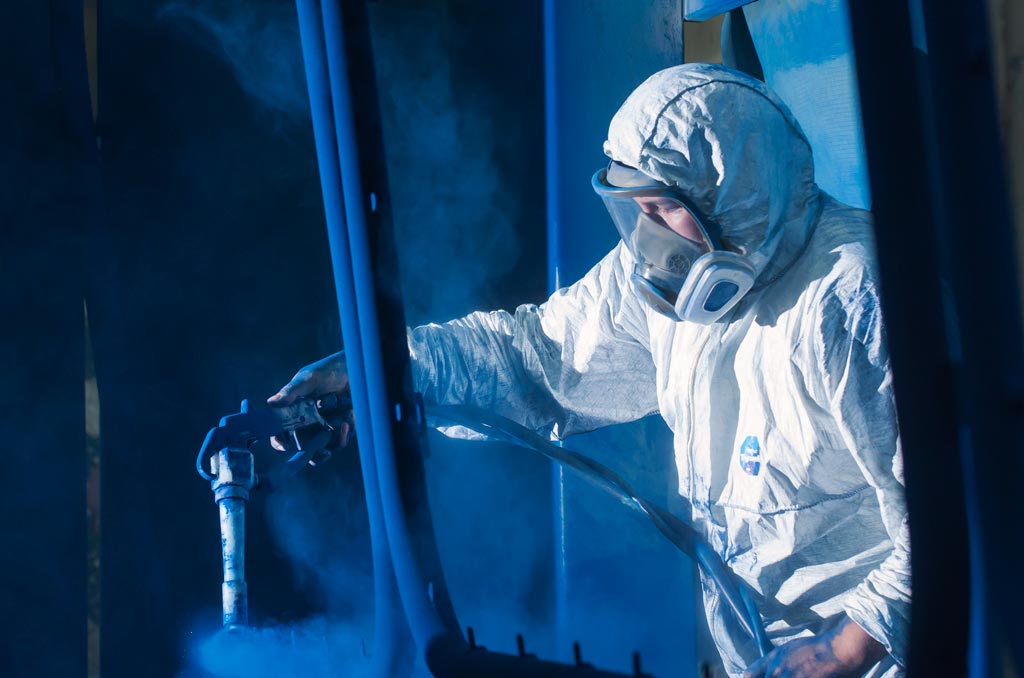 Profissional realizando pintura em cabine especializada